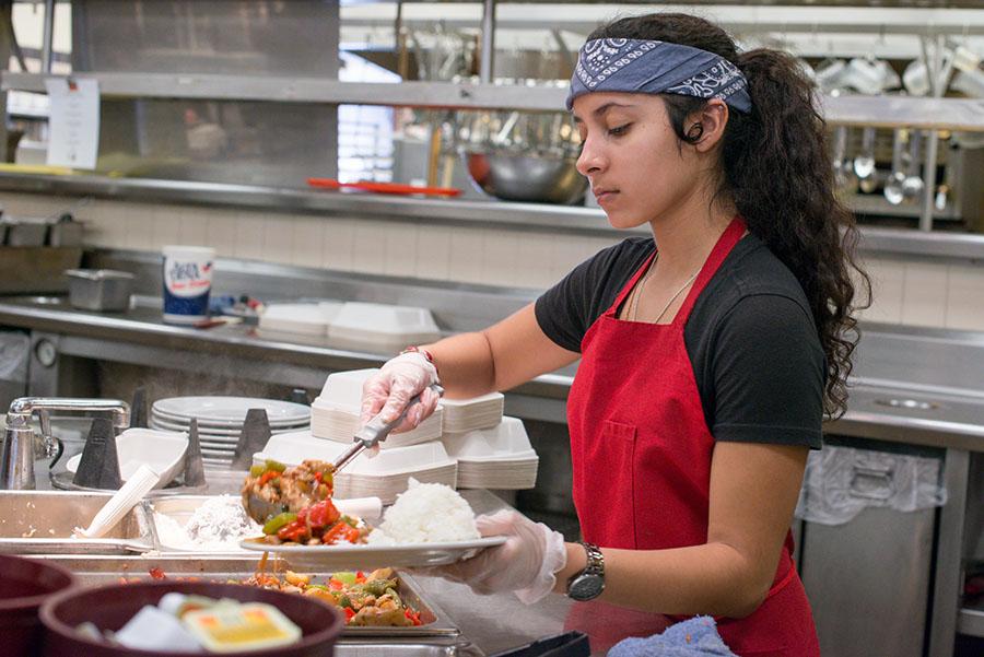Marina Flores, 19, communication major, puts together a food order in the East Campus Cafeteria at City College. The food handlers are now required to wear gloves when working with ready-to-eat food.
