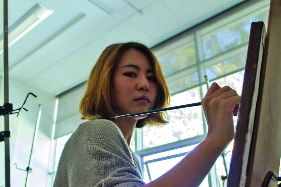 Seeon Kim, who has artwork on display in the Creation and Chaos exhibit, paints her next piece on Feb. 19, in the Humanities Building of City College.