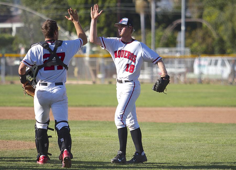 Catcher Patrick OBrien (No. 27) high-fives pitcher Kit Larson (No. 18) after getting the final out in a win against Oxnard College on Tuesday, March 18, at Pershing Park in Santa Barbara. Larson pitched the last two innings of the game en route to a 4-2 Vaqueros victory.