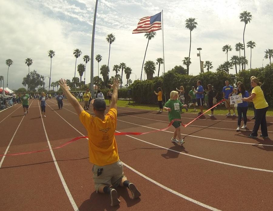 Allison Hoerf from Santa Barbara High crosses the finish line of the 50-meter run as Cameron Stewart cheers on the rest of the field Friday, April 25, at La Playa Stadium in Santa Barbara. The sixth annual Special Olympics Southern California School Games had more than 250 athletes from 26 schools in the Santa Barbara area.