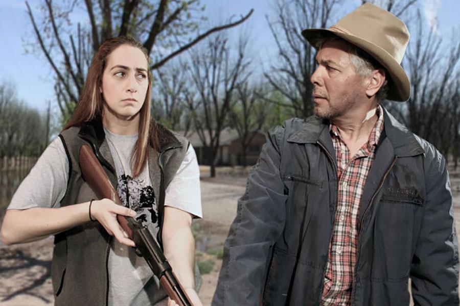 A woman with a gun stares at a man with a hat who stares back with a confused look on his face.