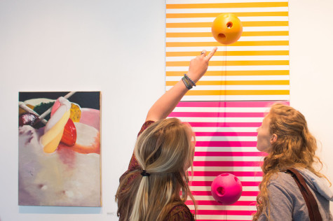 Keeley Thompson, left, and Etain Hiller inspect small astronauts inside Charles Starr's piece entitled "Lost In Space." His piece was featured in the Annual Student Exhibition in the Atkinson Gallery at City College, on April 25.