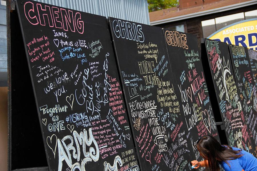 A woman writes with chalk on the Art Wall of Remembrance at 6550 Pardall Street, Isla Vista, on May 27.