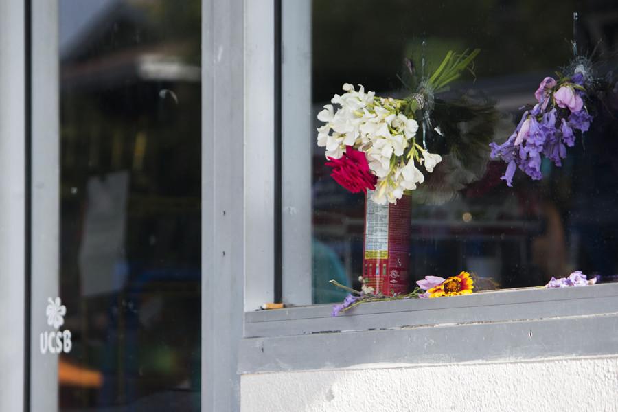 Flowers rest in bullet holes from Elliot Rodgers rampage at IV Deli Mart on Saturday, May 24, on Pardall Road in Isla Vista, Calif. UCSB student, Christopher Martinez, 20, was shot by Rodger in front of the market Friday night. Since then, Isla Vista residents have created memorials at various crime scenes.