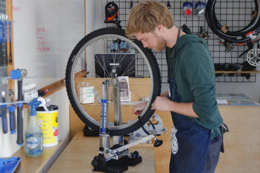 Student worker Kevin McClintock works on straightening a student's wheel at the new Bici Centro station, Wednesday, Feb. 18, located on the East Campus Bridge entrance at City College. This new do-it-yourself bike shop is open from 10 a.m. to 2 p.m. Monday through Thursday.