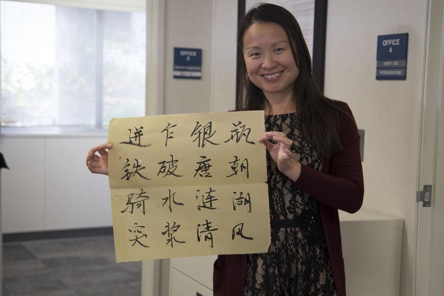 Yan Service, admission coordinator and club adviser for the Chinese Scholars and Student Association, holds up a calligraphy piece made by student Cheng Chen, Thursday, Feb. 19, in the International Student Services Building on City College’s East Campus.