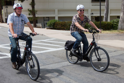 Bookstore Services Director Paul Miller and Administrative Assistant Jesse Valentine Felix ride two of City College's five new electric bikes, Friday, April 24, in the driveway on East Campus. These electric bikes, along with two hybrid cars, are available for employees during the day to run errands; also to take home and use as transportation to and from school.