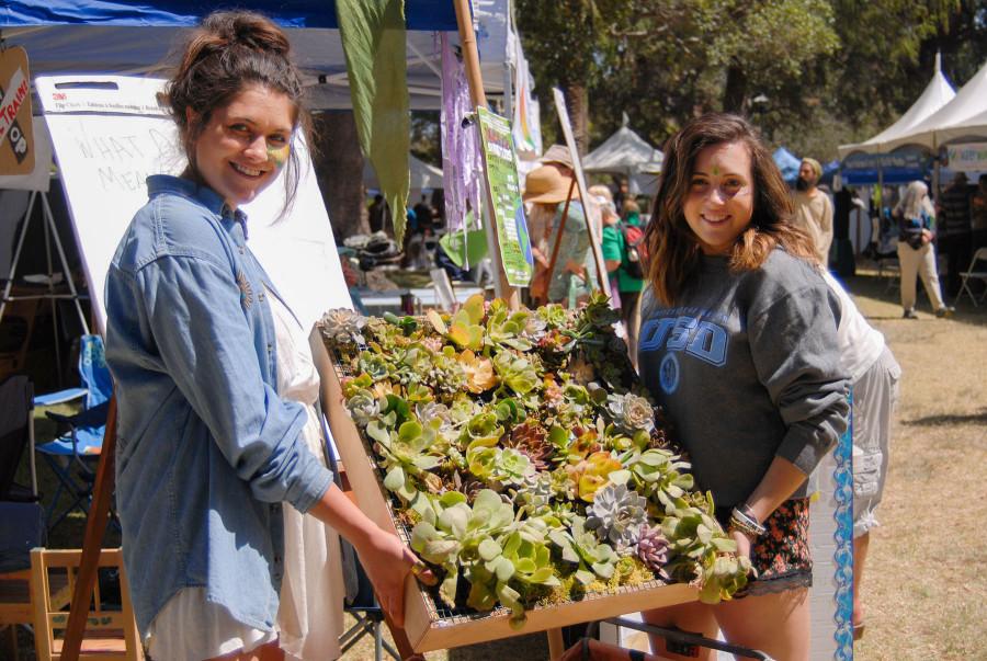 City College students Marisa Merola (left) and Sofia Silva display a sample of a green wall they are building in their Environmental Studies class, Projects in Sustainability, Sunday, April 19, at the Santa Barbara Earth Day Festival in Alameda Park. The completed green wall will consist of different types of plants that hang vertically and will be displayed in the Luria Library at City College.