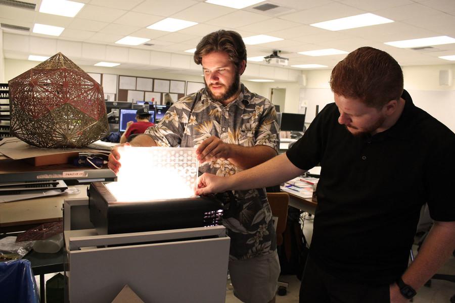 Makerspace lab staff Dakota Lepori and Marcus Stollmeyer are finishing a sign displaying their logo, created using the new 3-D laser printers, Wednesday, Oct. 14, in the Occupational Education Building Room 114 at City College.