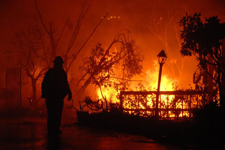 A Los Angeles City Firefighter surveys the fire damage on Camino Alto just after midnight on Friday, Nov. 14, 2008, in Santa Barbara. Fire crews from all over the state came to assist in firefighting efforts during the Tea Fire.