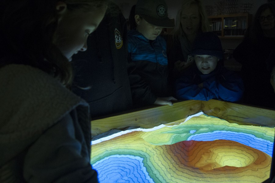 A volunteer of science day lets children from the audience play in the augmented reality sandbox, on Saturday, March 5, in the Earth and Biological Science Building at City College. The augmented reality sandbox maps the topography of the sand box in real time using a projector, and an Xbox Kinect.