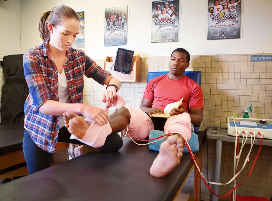 Danielle Barkey places therapeutic electrodes on Deshawn Phelps, track and field sprinter, on Thursday, March 11, at the City College Athletic Training Center in Santa Barbara, Calif. Barkley is enrolled in PE 290, a class which enables students to try out different jobs in their field in exchange for four transferrable units.