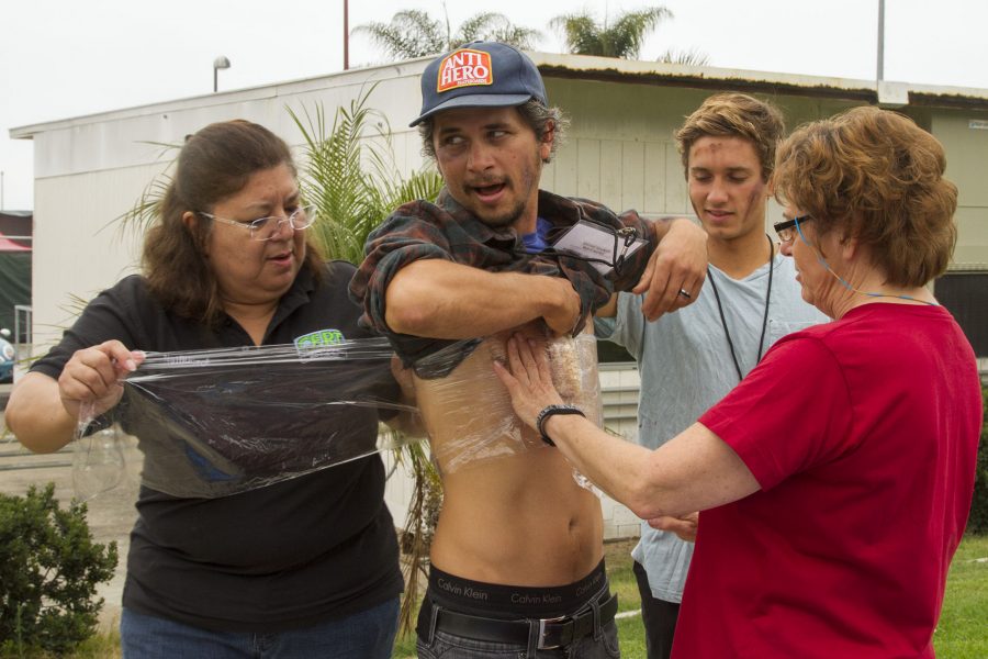 Participants in a City College disaster preparedness exercise wrap a bag of Rice Krispies around student Brett Hall Friday on East Campus. Yolanda McGlinchey (from left), a manager at the Office of Emergency Services, is joined by student Josh Raymond and instructor Justin Haagen. The Rice Krispies Treats simulate a severe chest injury that team members are trained to look for.