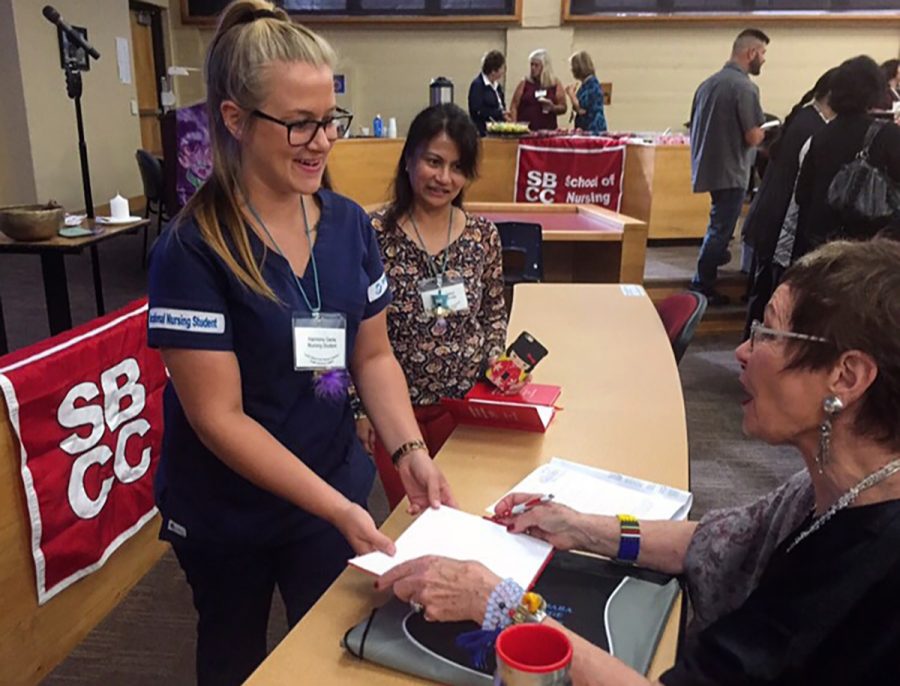 Nursing student Harmony Dante receives an autograph from Dr. Jean Watson before her introduction Friday, Sept. 16, in the City College Administration Building. Watson, who is a renowned educator in nursing, came to City College to talk to nursing students and staff about the importance of compassion in the profession.