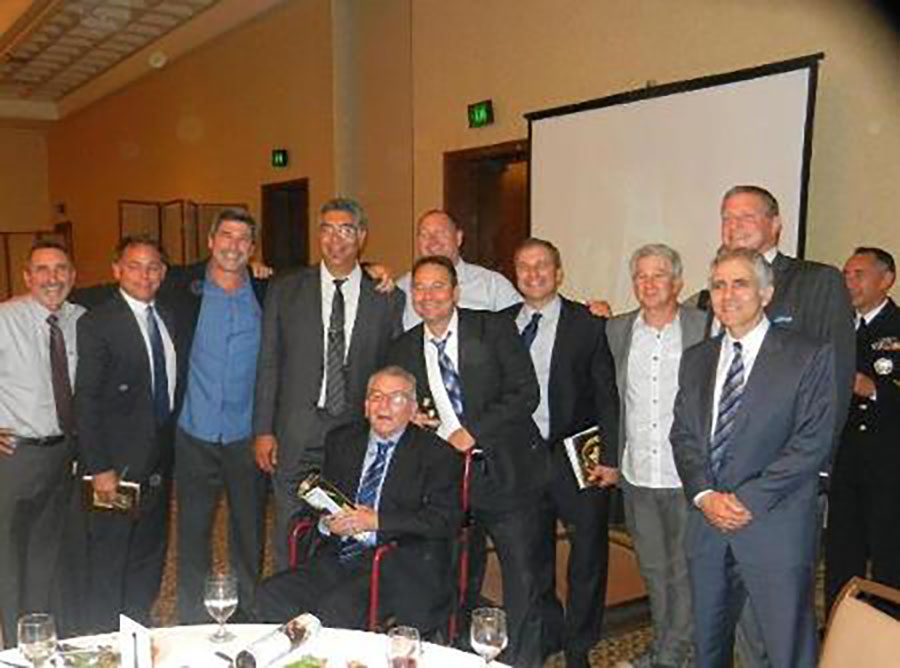 Coach Frank Carbajal seated in front of some of his former players.