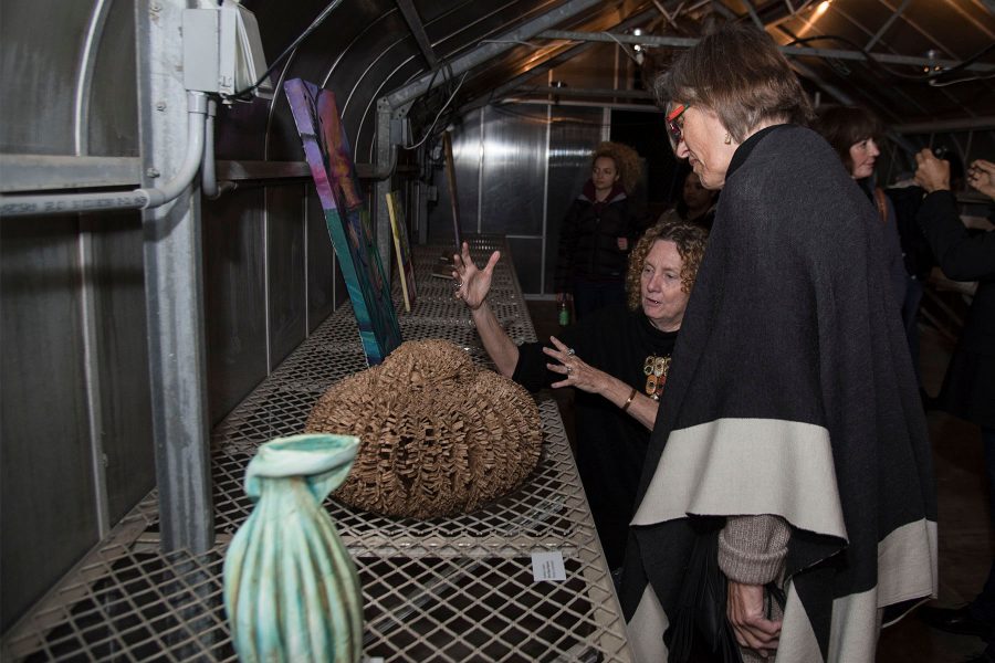Artist Kathryn Lubahn explains to Dr. Chella Courington how she made her art piece “Bird Seed Basket” on Tuesday, Nov. 29, City College East Campus green house. The student art exhibition was called Garden Observations and had various student art works on display.