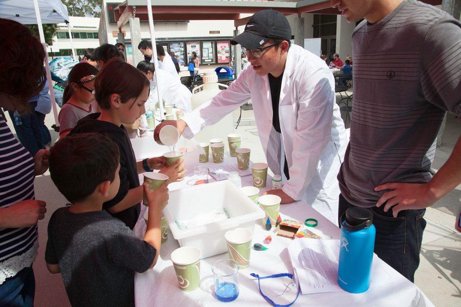 From left, Luis De la Palma and Alejandro Carvales show children how to make colored salt on Saturday, March 18, outside the City College East Campus Center for the 4th annual Science Discovery Day.