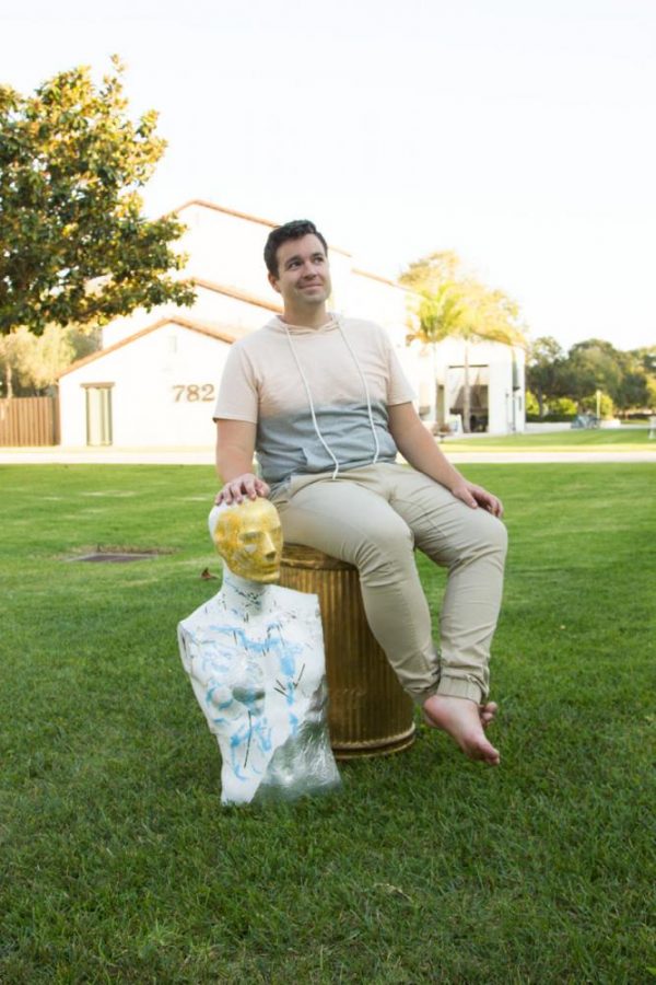 City College art student Bryan Austin Gillison, sitting on a golden trash can he uses as a pedestal, outside his apartment Friday, Oct. 13, in Goleta, Calif. “The golden trash can is a good metaphor for what I do because it’s like gilded trash,” said Gillison