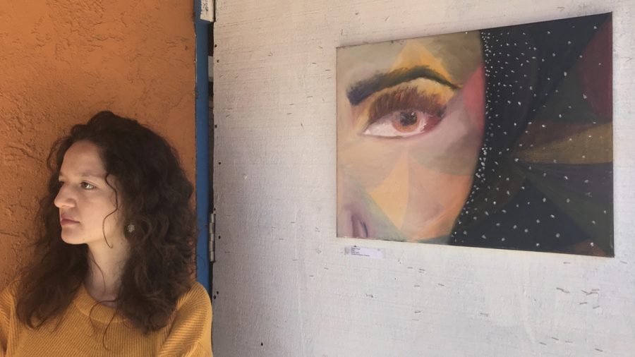 Camila Rodriguez stands next to her acrylic painting “Slowly Freed” as guests come to the ART 118 pop-up show on Friday, March 23, at the Biko House in Isla Vista.