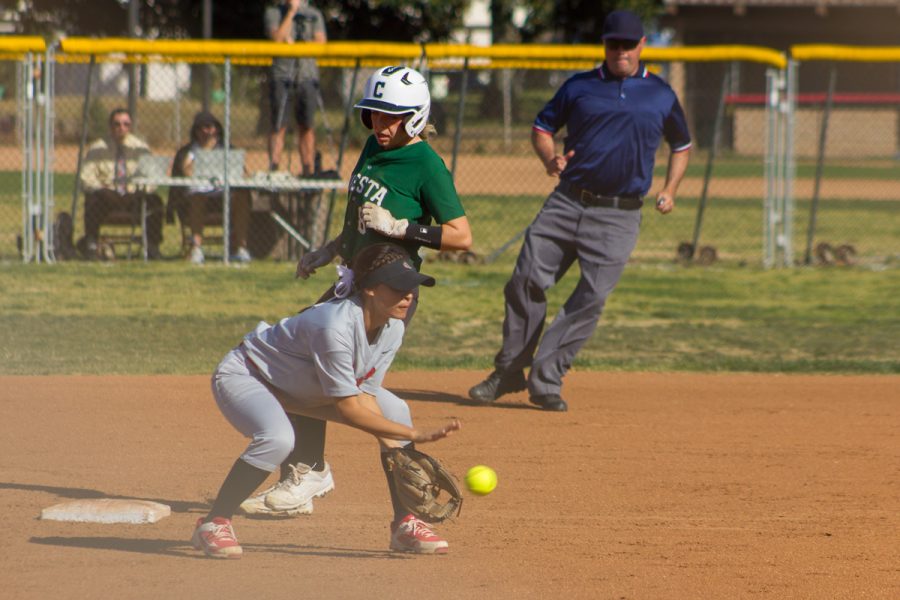 Jasmine Manson scoops up a grounder at third base while Dayna Maser runs in.