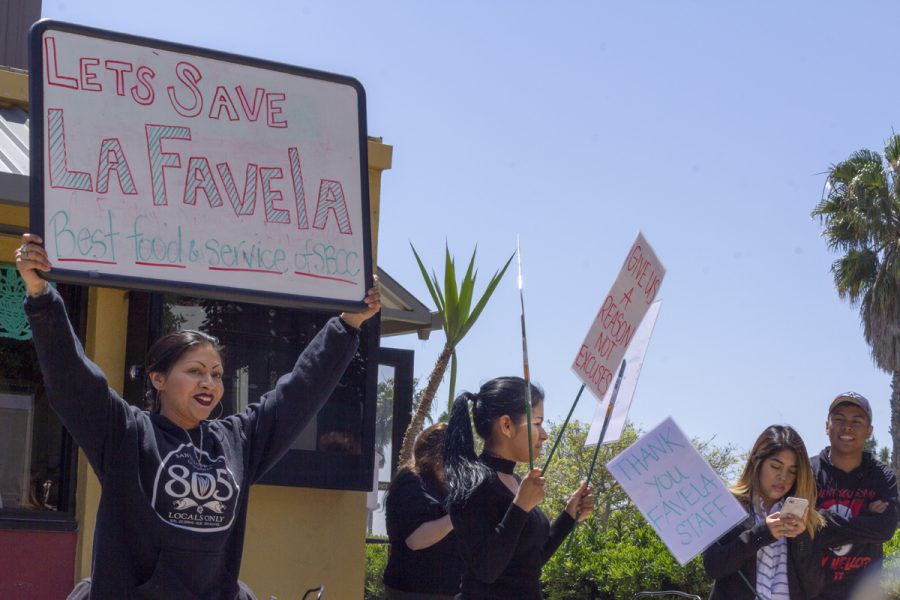 Alondra Lazaro Gonzalez, Denise Lazaro, and Nereida Rangel hold signs in protest April 16 outside the Favela cafe on East Campus at Santa Barbara City College. The students are protesting to bring awareness of student workers losing their jobs with little notice, and the loss of diverse, comfort food on campus.