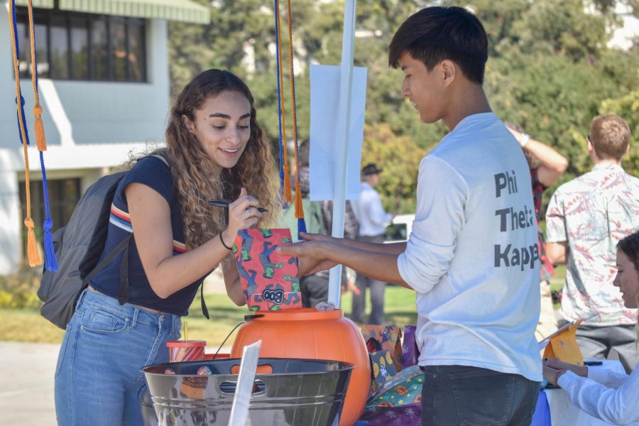 Newara Brosan-Faltas addresses a candy bag with the help of Christopher Lee, Phi Theta Kappa president, for the Phi Theta Kappa Trick or Treat fundraiser on Thursday Oct. 24, 2018, at City College in Santa Barbara Calif. All of the fundraiser proceeds will be donated to the Alzheimer's Foundation.