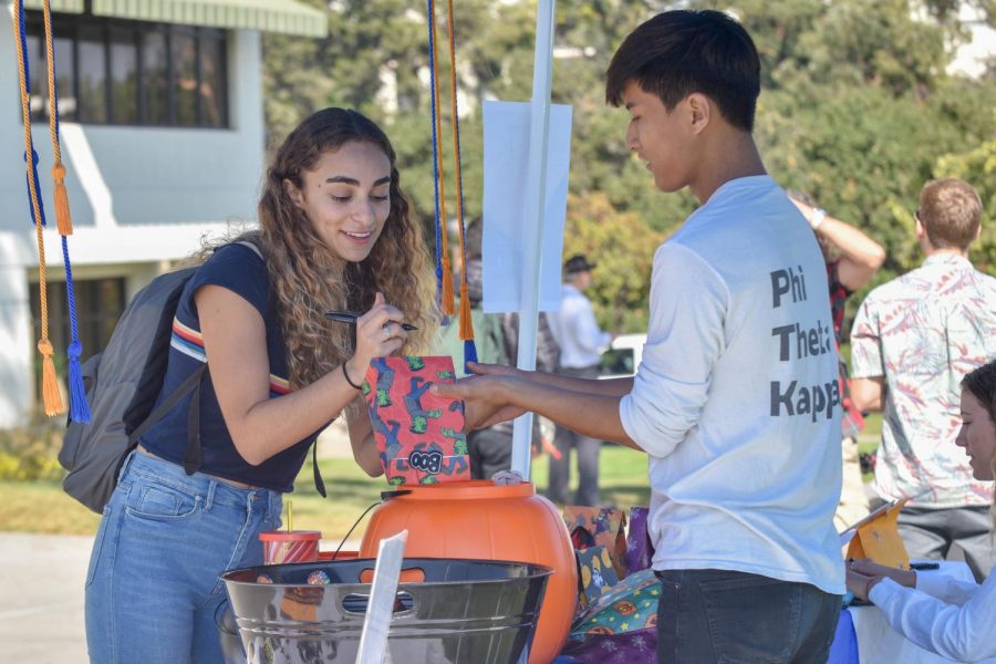 Newara Brosan-Faltas addresses a candy bag with the help of Christopher Lee, Phi Theta Kappa president, for the Phi Theta Kappa Trick or Treat fundraiser on Thursday Oct. 24, 2018, at City College in Santa Barbara Calif. All of the fundraiser proceeds will be donated to the Alzheimers Foundation.