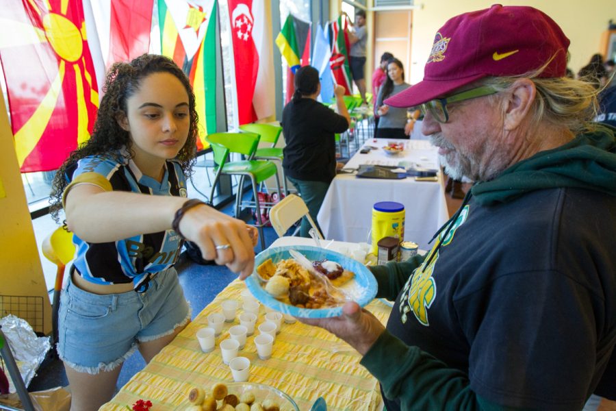 Mariana Dos Santos serves Jon Santala pão de queijo at the annual International Food and Culture Fair hosted by the City College Ambassadors on Friday, Nov. 16, at the East Campus cafeteria at City College in Santa Barbara, Calif. Pão de queijo, or Brazilian cheese bread, is a popular snack and breakfast food in Brazil.