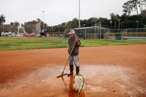 Bruce Falen takes a brief pause from dispersing water gathered in puddles from recent rains on Thursday, Feb. 28, 2019 on the Pershing Park City College softball fields in Santa Barbara, Calif. “I have been here since 9 a.m. and I still have a lot more to do,” said Falen. “It just doesn’t drain enough here, especially when there is no wind.”