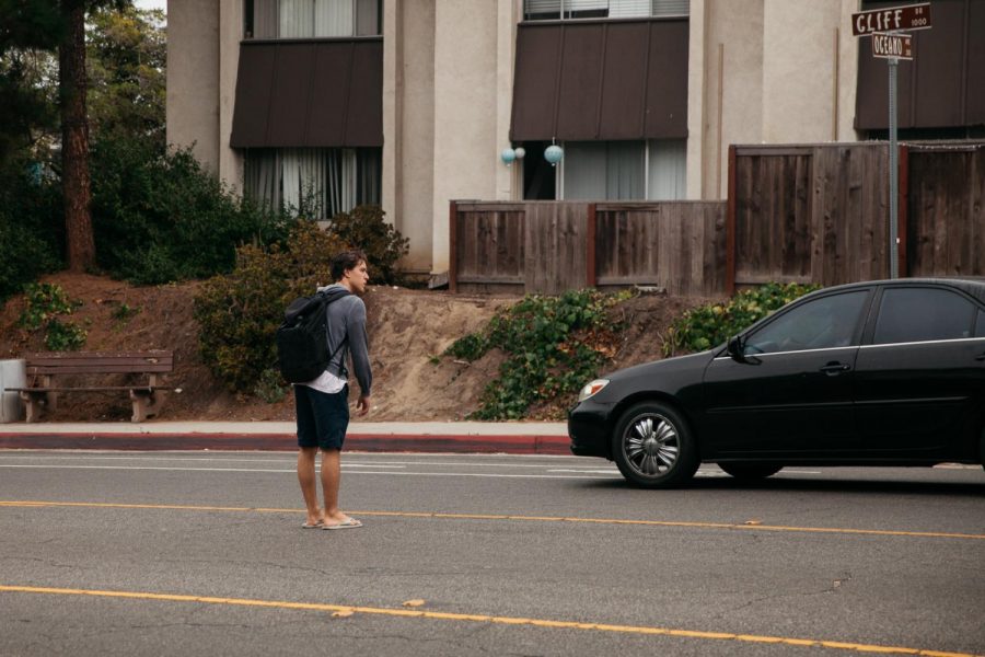 City College student Pedro Saraiva waits in the center turn lane for a gap in traffic to cross Cliff Drive near the West Campus entrance on Monday, Sept. 23, 2019, in Santa Barbara, Calif. There is no nearby crosswalk offered to students who walk to and from the West Campus entrance causing dangerous jaywalking and long wait times to cross Cliff Drive.