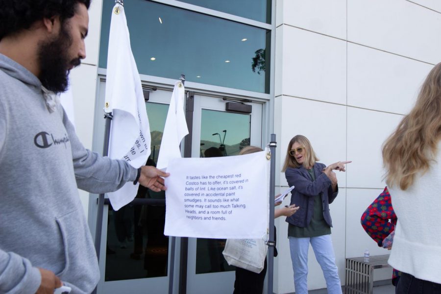 City College Electrical Engineering student Angel Caballos reads a riddle printed on a flag created by Jane Mulfinger for her solo exhibition West is South in the Atkinson Gallery on Oct. 4, 2019, in the Humanities building at City College in Santa Barbara, Calif.