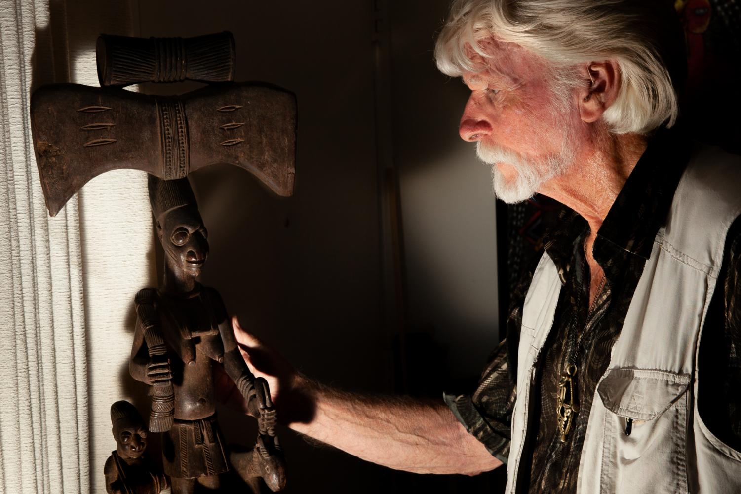 Ron Atwood admires a Shrine sculpture to the powerful Shango god of thunder of a female worshiper with a thunder celt headpiece and talking drum, one of his most valuable and prized pieces.