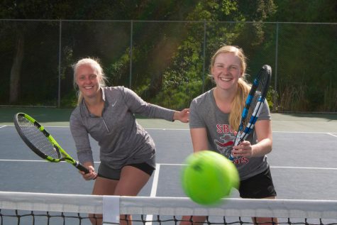 Joica Buyse serves the tennis ball while her twin sister Jamaica stays ready for the response of an opponent on March 9, 2020, at Pershing Park tennis courts in Santa Barbara, Calif. Joica and Jamaica are second-year tennis players from Izegem, Belgium.