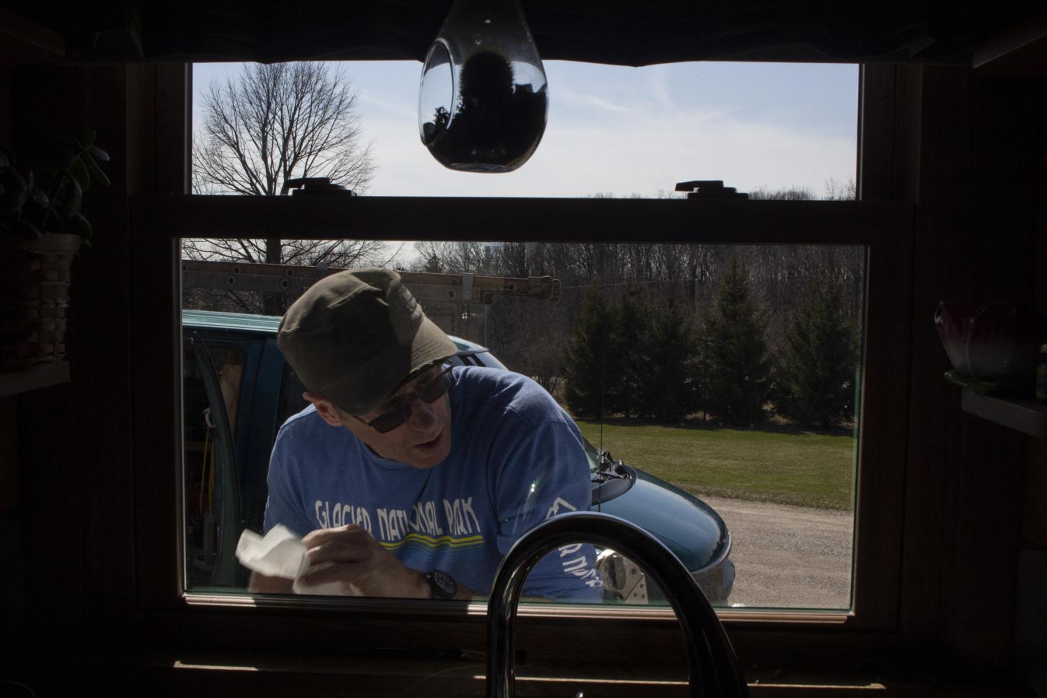 Mitch Schrage wipes the sawdust off a new screen he installed on his house on April 2, 2020, at his home in New Holstein, Wis. Schrage is used to work picking up this time of year, and with the shelter in place order in act, his business has not been affected at all, if anything has increased.