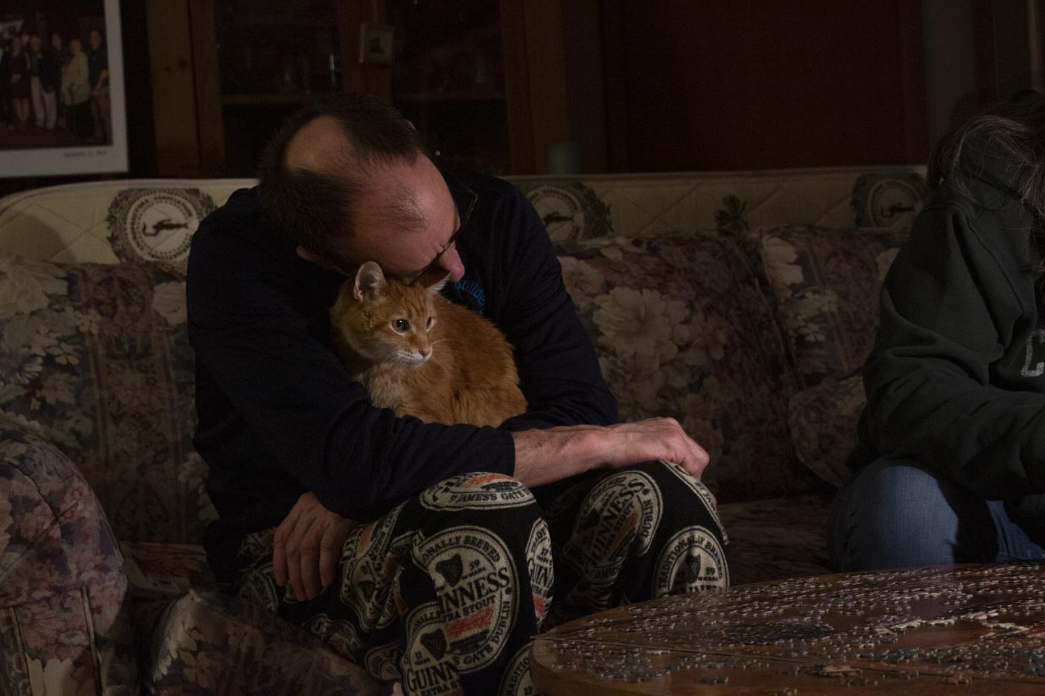 Mitch Schrage takes a break from putting a puzzle together with Terese Brunner to hug their cat Sully on April 6, 2020 at their home in New Holstein, Wis. Schrage finds comfort in the company their pets provide during these stressful times.