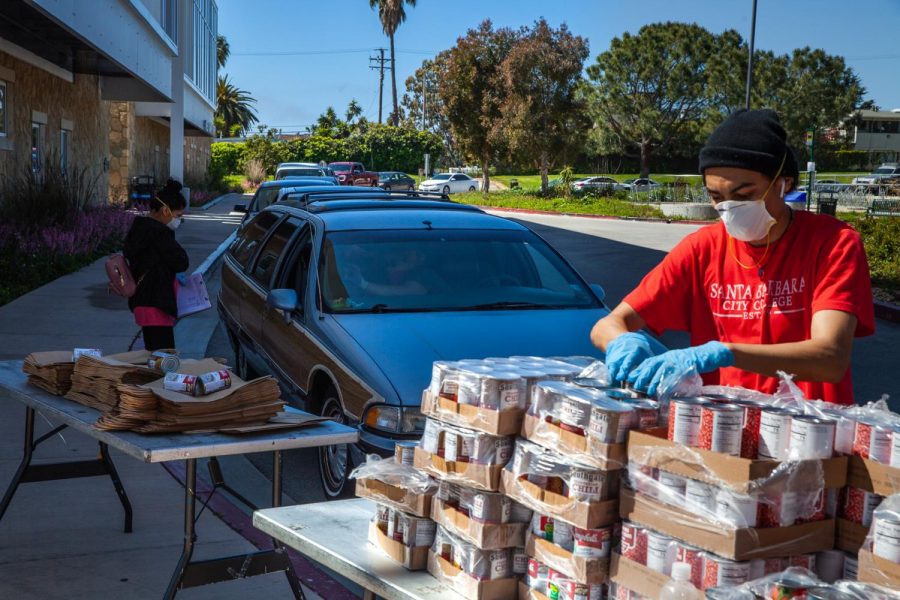 From left, Equity Department employees Alondra Lazaro and Juwan Vega work the drive-through food drive line on Wednesday, April 1, 2020 on the West Campus roundabout at City College in Santa Barbara, Calif. Lazaro took specific orders and asked questions for a survey while Vega and other employees bagged items for drivers and walk-up students.