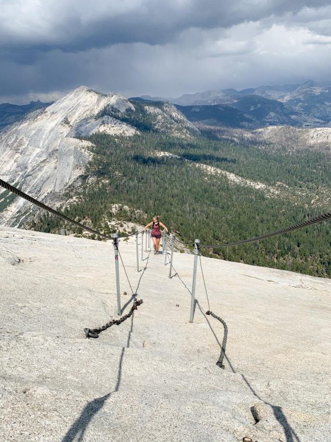 Angi Daus climbs up Half Dome on July 23, 2020 in Yosemite, Calif., using the support cables installed in 1920. The cables are an example of national parks becoming more convenient and accessible, but not without trade-offs.