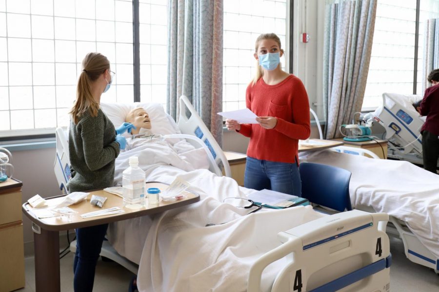 Brea Cook (left), and Cara Christian practice caring for a simulated tracheostomy patient on Feb. 9 2021 at the Nursing Lab in the City College Administration building in Santa Barbara, Calif. Each pair of students work together, learning the entire process of setting up a sterile tray of supplies and changing the dressings where the patient's breathing tube would be placed. 