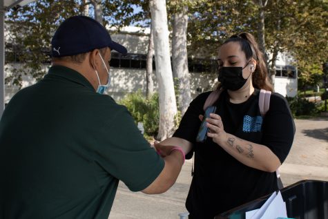 City College employee Mauro Escamilla applies a wristband to first-year international student Sarah Provoost on Thursday, Sept. 2, 2021 at City College in Santa Barbara, Calif. Students must fill-out a survey online or in-person and receive a wristband prior to entering buildings on campus.