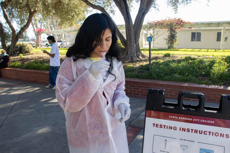Nurse Ariana Romo demonstrates how to properly take a COVID-19 spit test on Feb. 7 at City College in Santa Barbara, Calif. In order to enter a building on City College's campus, individuals need to upload their vaccination status or proof of exemption, submit a negative COVID-19 test once a week and wear an N95 or KN95 mask.