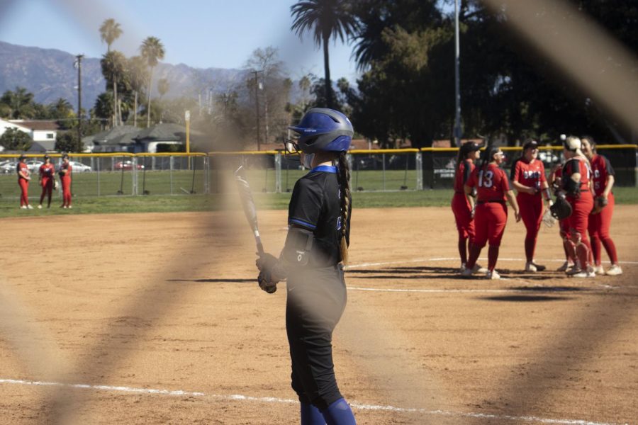 The City College Vaqueros Softball team plan their next team while a San Bernardino Wolverine warms up for her teans at bat on Feb. 5 at City College's baseball diamond in Santa Barbara, Calif. The San Bernardino Wolverines eliminated the City College Vaqueros two games to zero.