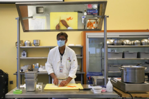 Chef Stephane Rapp teaches his Principles of Pantry class how to cut a carrot from his teaching station at the front of a socially distanced class where each student has his or her own workstation on Jan. 25, 2021 in the cafeteria where the culinary department temporarily held classes over the COVID-19 pandemic at City College in Santa Barbara, Calif.