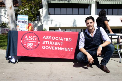 Associated Student Government Vice President Cameron Black squats besides the ASG's table during club day on April 5 at City College in Santa Barbara, Calif. Black, who has been involved with the ASG since spring of 2021, is in his final semester at City College.