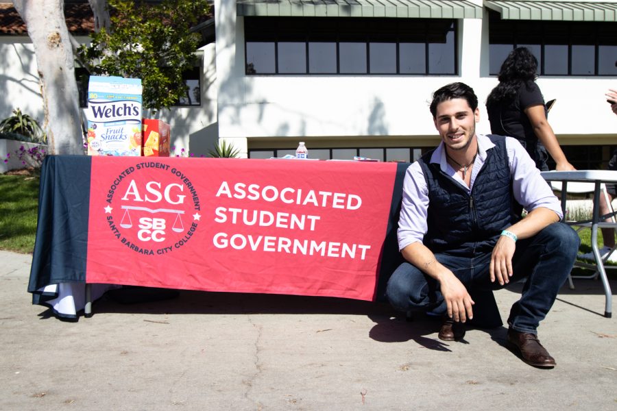 Associated Student Government Vice President Cameron Black squats besides the ASGs table during club day on April 5 at City College in Santa Barbara, Calif. Black, who has been involved with the ASG since spring of 2021, is in his final semester at City College.