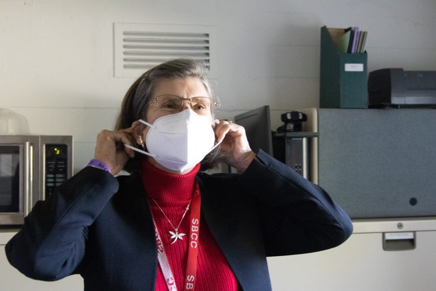Interim Superintendent-President Kindred Murillo demonstrates how to put on a KN95 mask on April 4 at City Colleges administration building in Santa Barbara, Calif. Although California recently lifted its mask mandates, City College still requires masks at all times while inside.