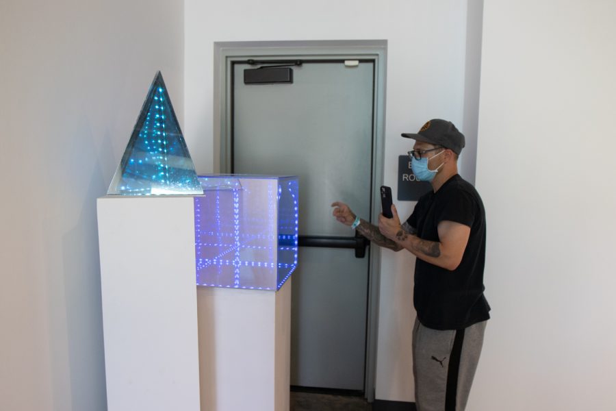 Art student Brenno Ressa makes last-minute tweaks on his pieces "Tesseract Cube" and "Triangle" on April 5 at the "Structure and Skin II" Atkinson Gallery pop-up exhibition at City College in Santa Barbara, Calif. The piece is made of acrylic plexiglass, LED tape lights and mirrors. 