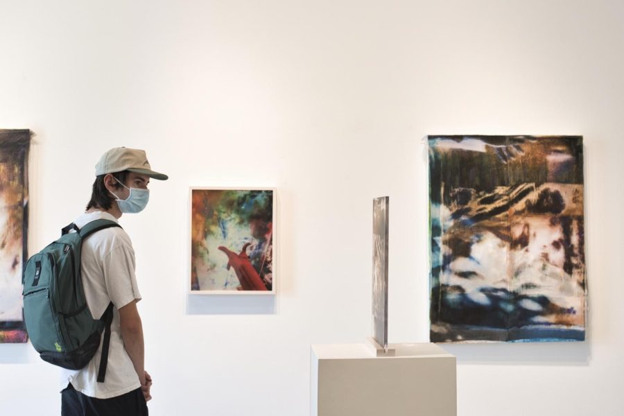 A student views art on platen plexiglass by Tamar Siegfried Rosa Halpern on Sept. 8, 2022, at the Atkinson Gallery at City College in Santa Barbara, Calif. The plexiglass medium of the piece generates new interpretive experiences as the viewer’s position and natural lighting alter the art display.