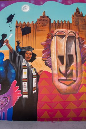 The final interactive quality of the mural on Friday, Sept. 16, is the UMOJA graduate raising her fist. The university behind her, Timbuktu, is one of the first universities in Africa.