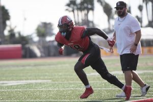 Linebacker Joseph Olsson (No. 48) sprints forward during a defensive drill at a daily football practice on Oct. 19 at La Playa Stadium in Santa Barbara, Calif. To his right stands Linebacker Coach Jackson Weed, who directed the training exercise.