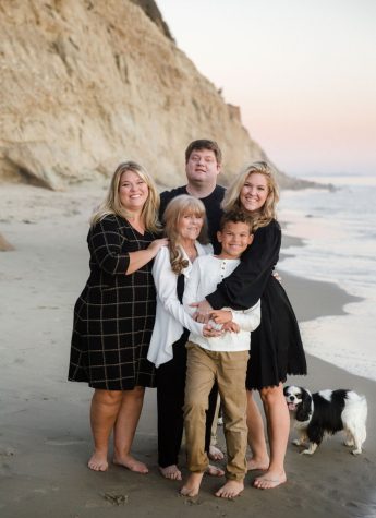 Laura, Tom, and Betsy Woyach, Holly Dennison (center) and Carter Woyach embracing each other for a family photo in the fall 2021 on a beach in Santa Barbara, Calif. Living in two countries, eight cities, and many houses, the Woyach family has a strong bond. After six months of planning a family photoshoot, Laura Woyach explains that her husband is the only one missing from the photo due to recovering from an illness but the family has always been a team regardless. “This is my squad, my peeps, they happen to also be my family,” Laura wrote. “We are lucky enough to still all stay together and get to live in beautiful Santa Barbara.”